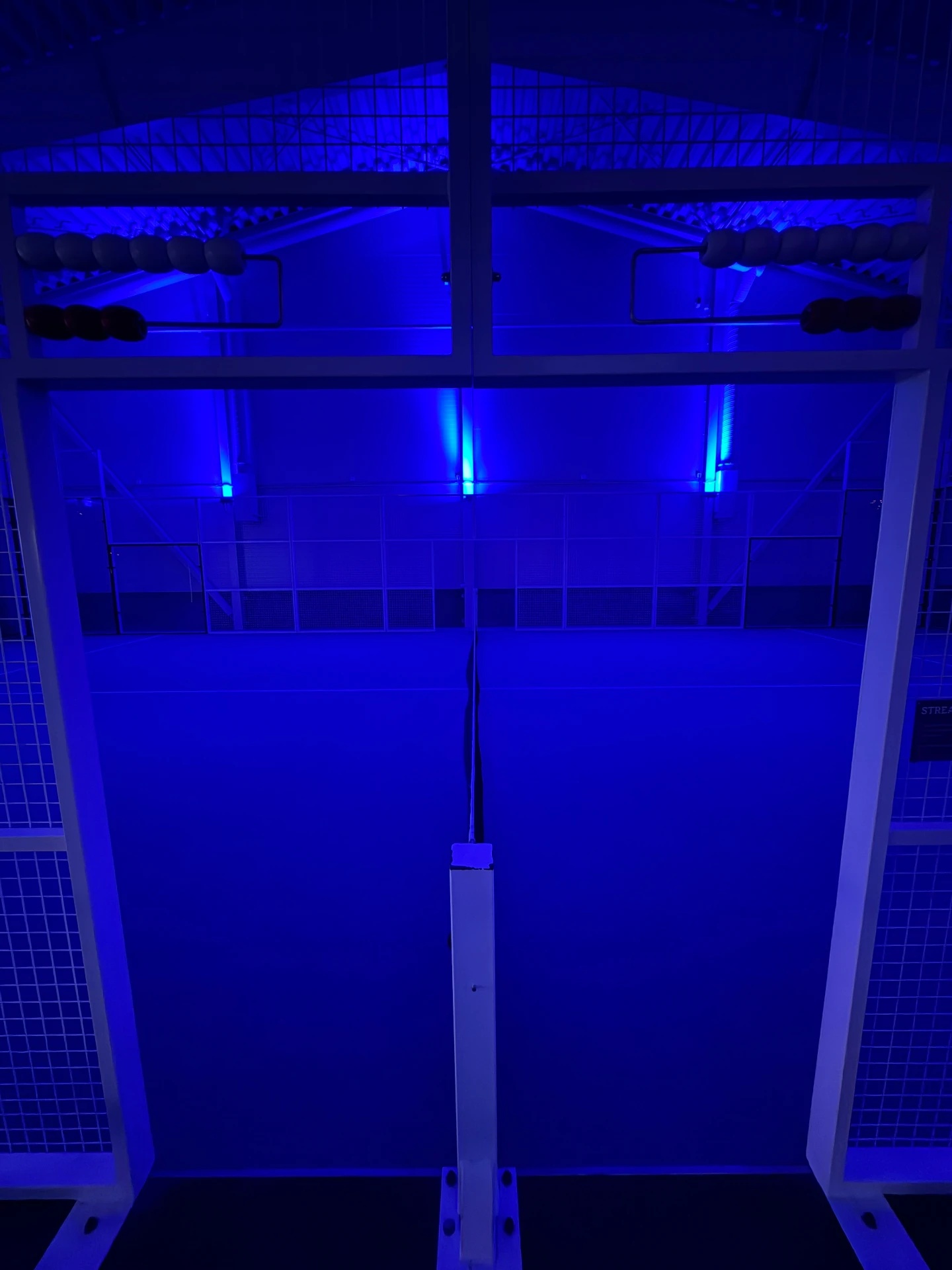 En padelbana i hallen med blå belysning