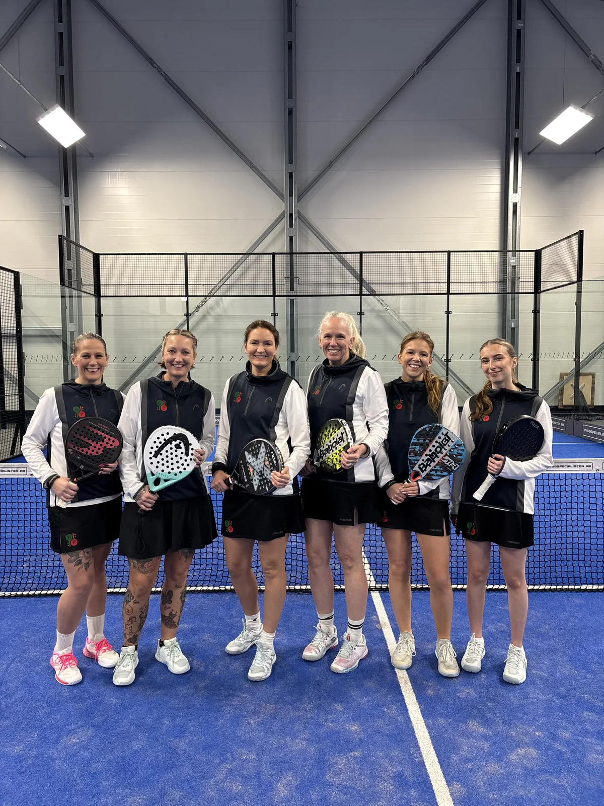 Föreningens damlag i klubbkläder med racketar på padelbanan